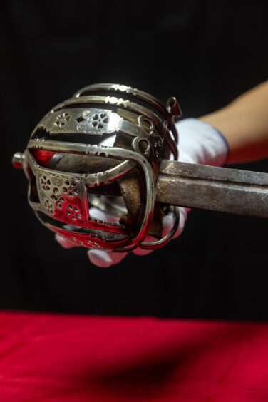 Hand holding elaborate metal sword handle