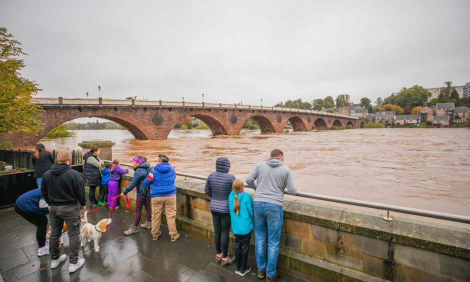Group of onlookers next to bridge at swollen River Tay in Perth