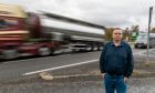 Fergus McCallum next to busy A9 at Pitlochry as blurred lorry and van go past