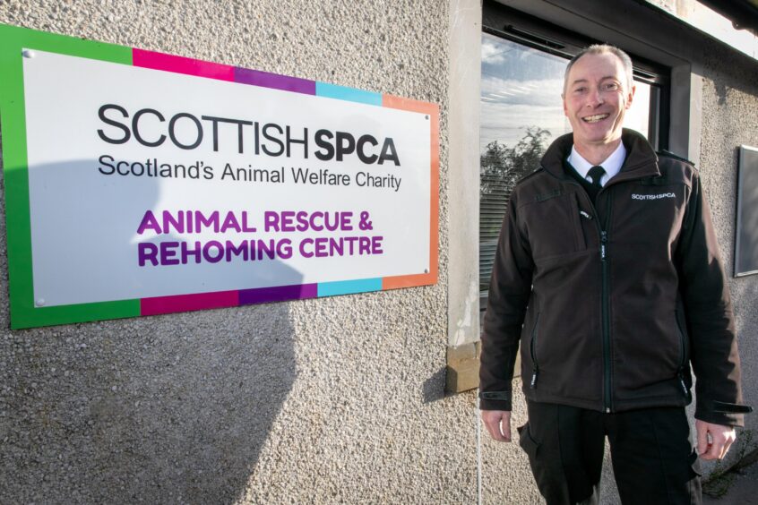 Angus SSPCA inspector Alastair Adams stands by a sign which reads "Scottish SPCA: Scotland's Animal Welfare Charity. Animal Rescue and Rehoming Centre." 