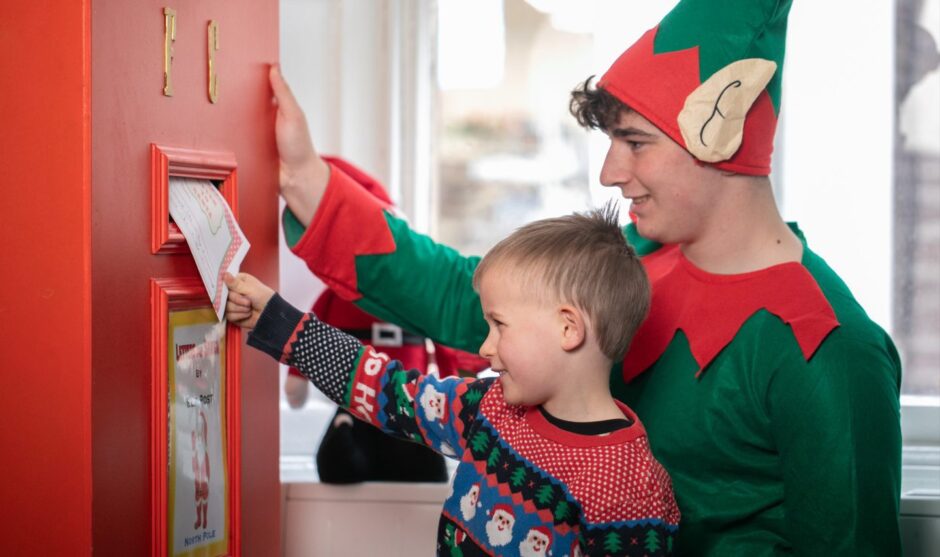 Taddy Maher, 5, posting letter at Santa's Post Office, Crieff, helped by Hamish Campbell in elf outfit