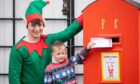 Taddy Maher, 5, posting letter to Santa with Hamish Campbell, dressed as an elf