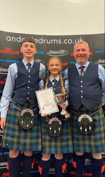 Flora McNab holding trophy in Glasgow with her brother and her dad by her side