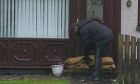 A resident puts sand bags outside his door as he leaves his house on River Street in Brechin. Image: Andrew Milligan/PA Wire.