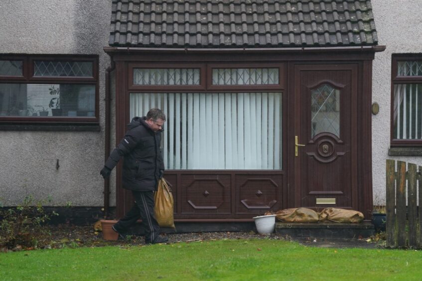 A resident puts sand bags outside his door as he leaves his house on River Street in Brechin during Storm Babet.