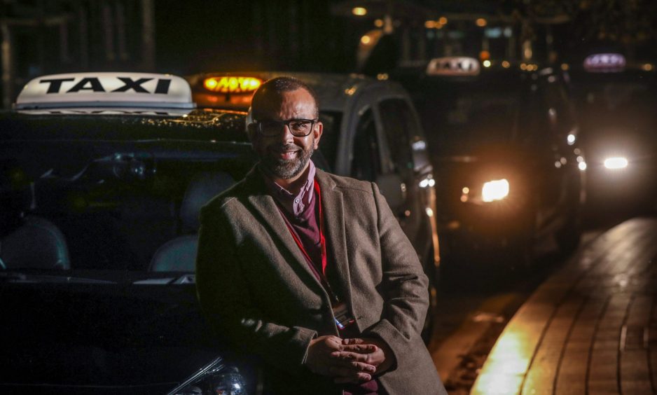 Driver Qaiser Habib posing outside his Dundee taxi.