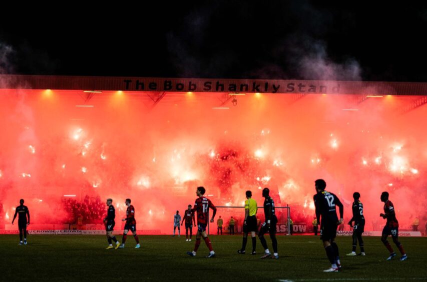 Rangers fans light up Dens Park's Bob Shankly Stand with pyros. 