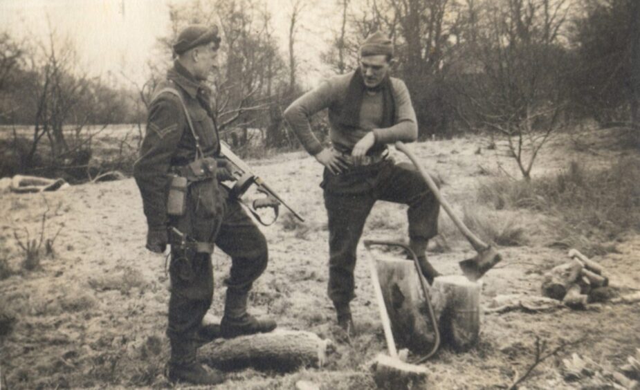 Two 2SAS soldiers training in Scotland in 1944, one holding a gun and other taking a break from chopping wood