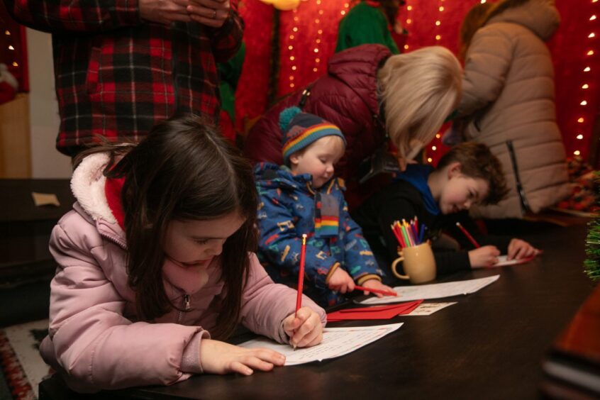 Children, deep in thought, writing letters at Santa's Post office, Crieff