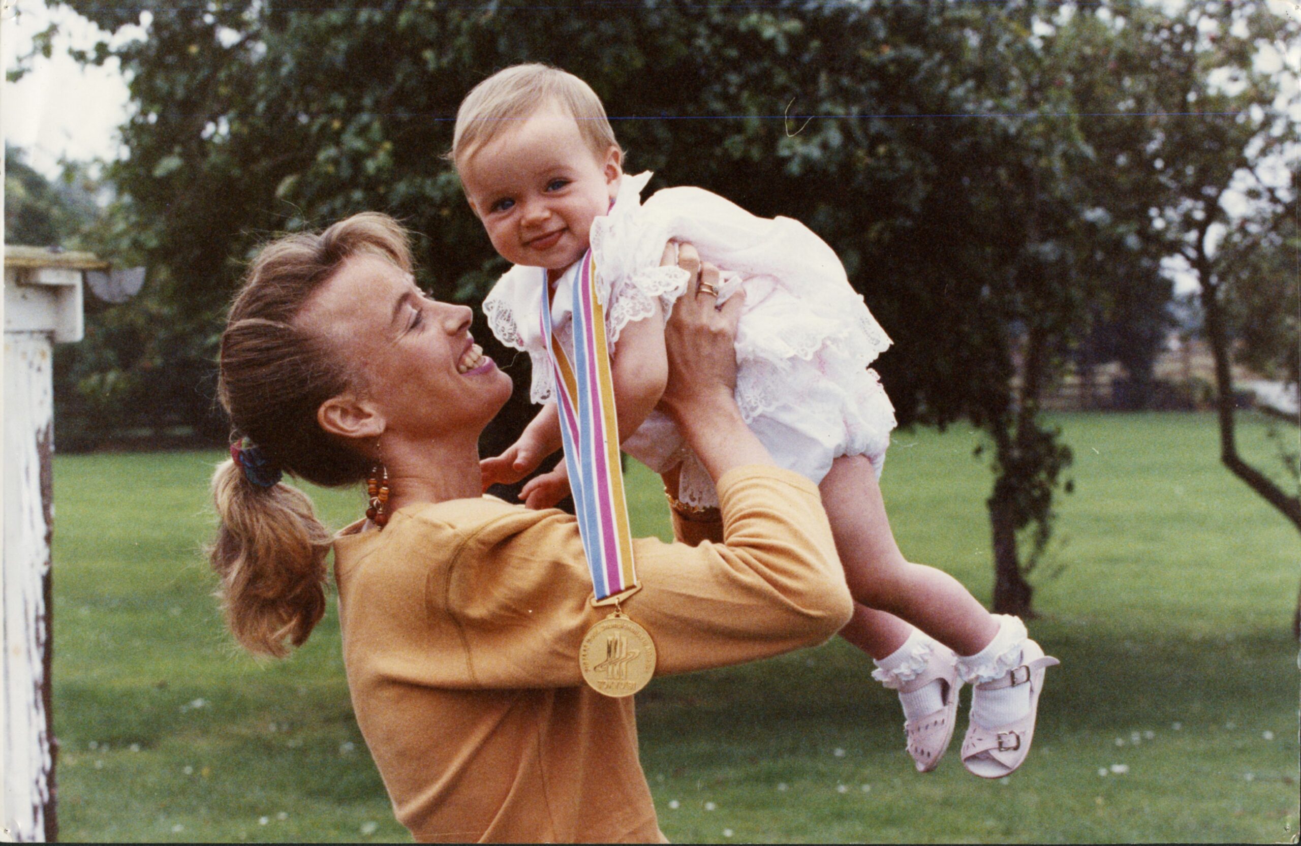 Liz McColgan holding daughter Eilish above her head in 1991. The baby is wearing a medal around her neck.