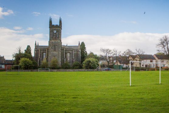 Errol park with football goal in foreground and church in background.