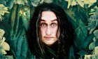 Comedian Ross Noble stares wide eyed at the camera as his face pops out from a background of green vines and yellow leaves.