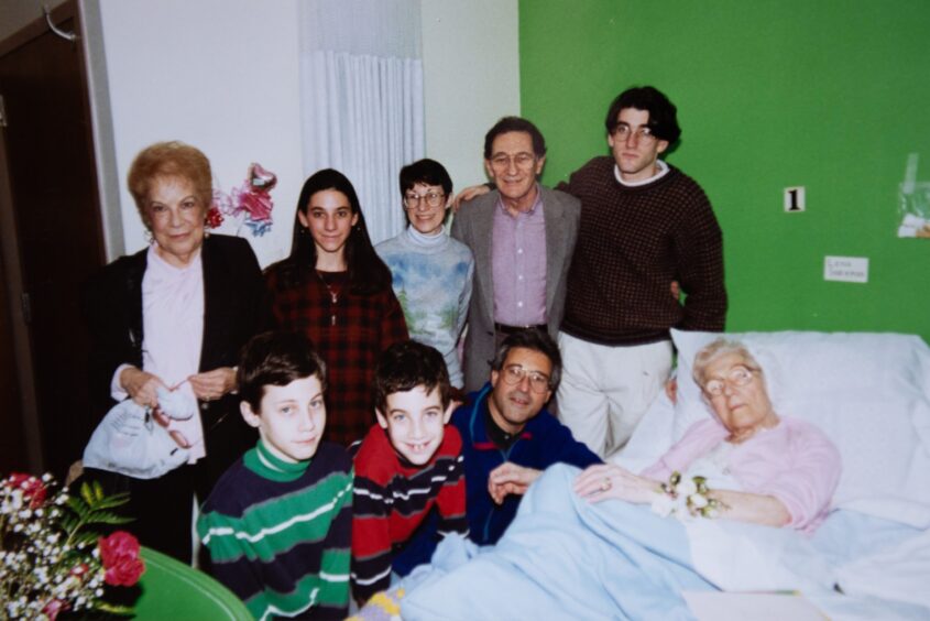 Image shows Lena Shachman in bed, surrounded by her family including great-grandson Bill Shackman, standing beside her.