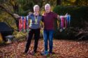 Lesley and Lawrence Richardson, both with arms outstretched and covered with medals from shoulder to wrist