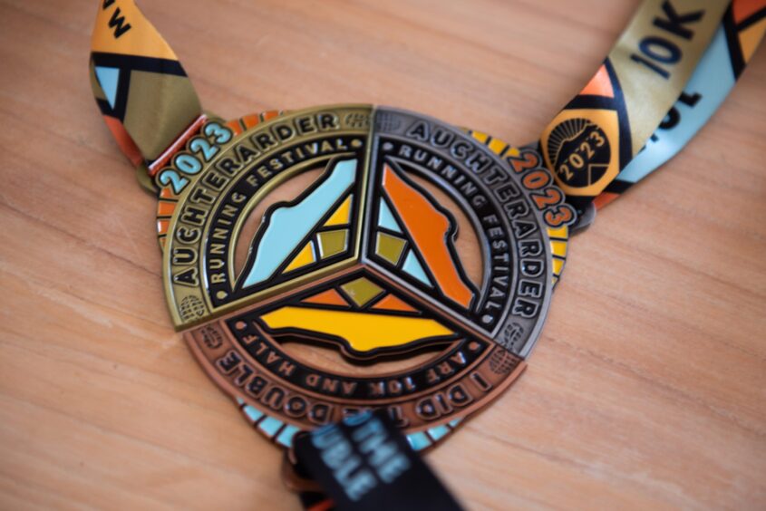 Three triangular shaped medals from the Auchterarder running festival, which join together to create a circle