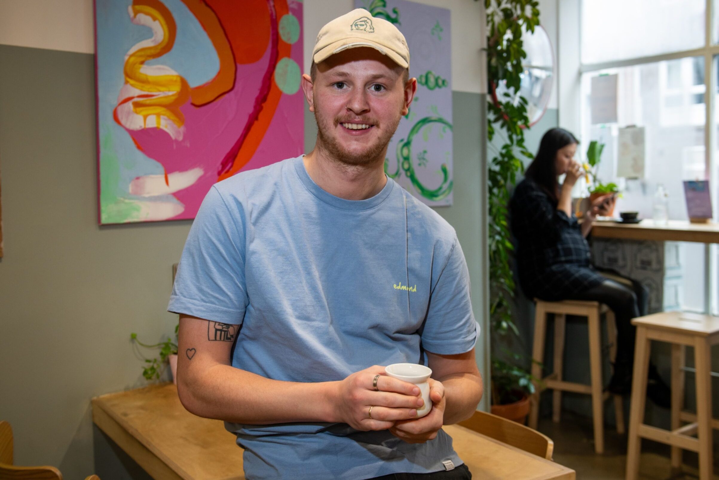 Barista Fraser inside EH9 Espresso holding a cup of coffee.