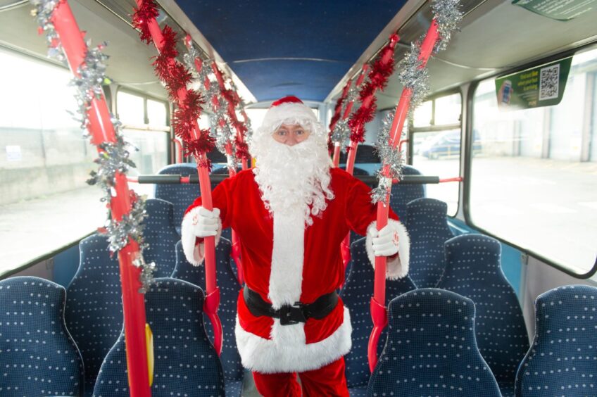 A person dressed as Santa on board a Christmas-themed bus
