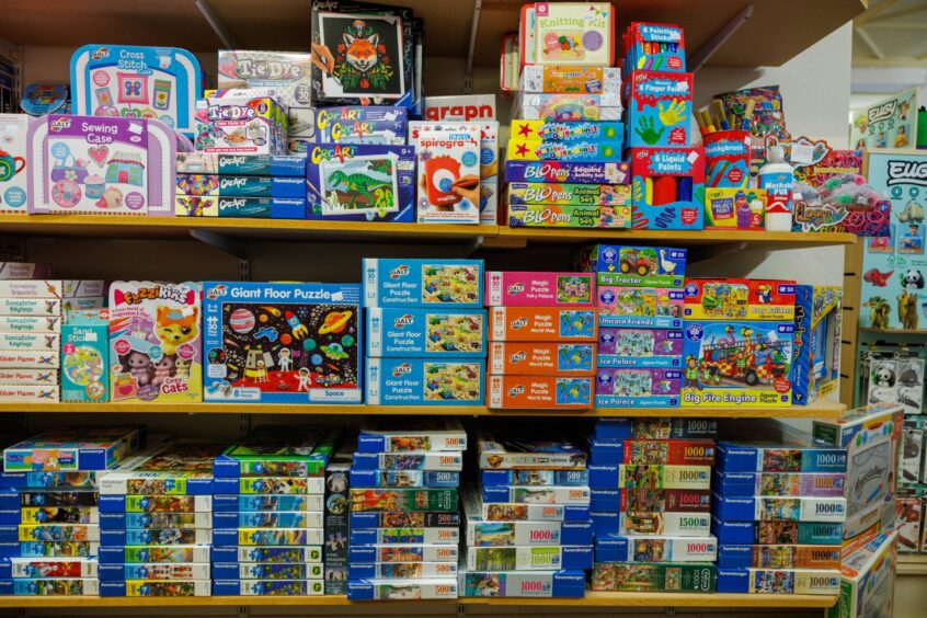 Image shows: shelves stacks with jigsaws and toys ready for Christmas.