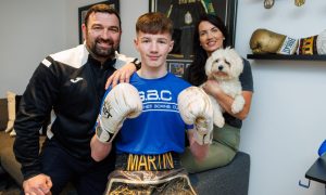 Reo Martin in his boxing gloves and kit with dad John, mum Leanne and dog Buddy.