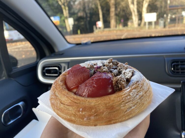 The spiced plumb and ginger crumble Danish from Aran Bakery in Dunkeld. A round Danish sat on a napkin with rosy red plumb and crumble topping. 