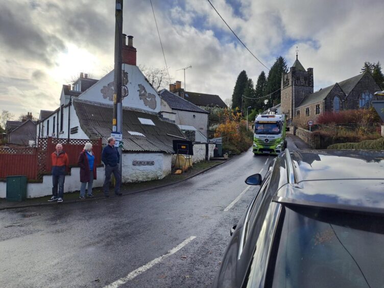 Gordon and Linda Low and Ian Pilmer at the bottom of Church Brae, Glenfarg, as a large tanker lorry comes down the narrow street taking up both lanes.