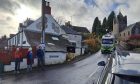 Three people standing beside narrow road in Glenfarg while a lorry drives down it
