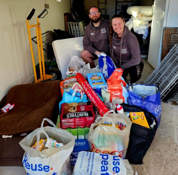Lisa and Gary Mulholland next to bags full of dog food.