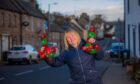 Corrina Robertson holding up Christmas decorations on Muthill main street