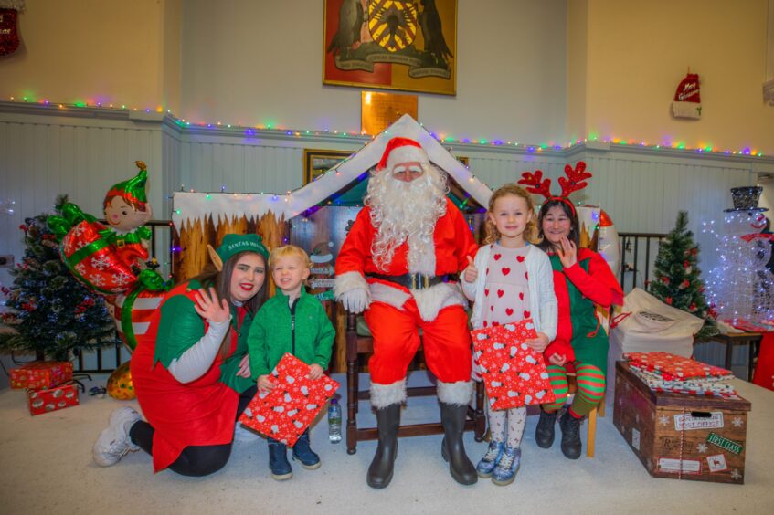 Sants in his grotto at the Aytoun Hall flanked by elves and two small children.