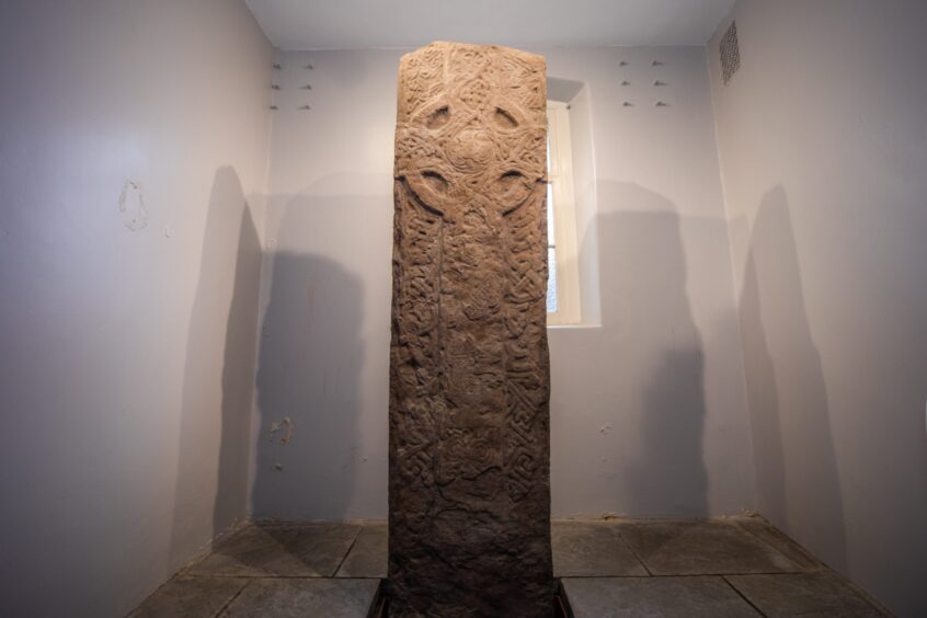 Standing stone with elaborate carved cross in a room in Crieff Town Hall