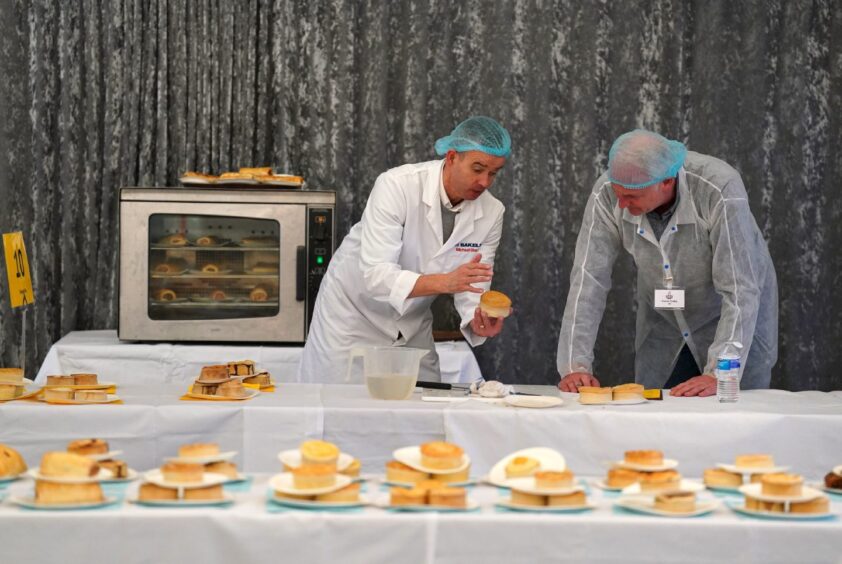 Two judges inspecting pies at the World Championship Scotch Pie Awards 