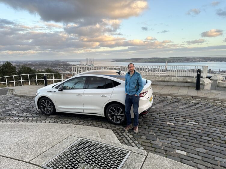 Reporter Jack McKeown with the Skoda Enyaq Coupe on top of the Law in Dundee. 