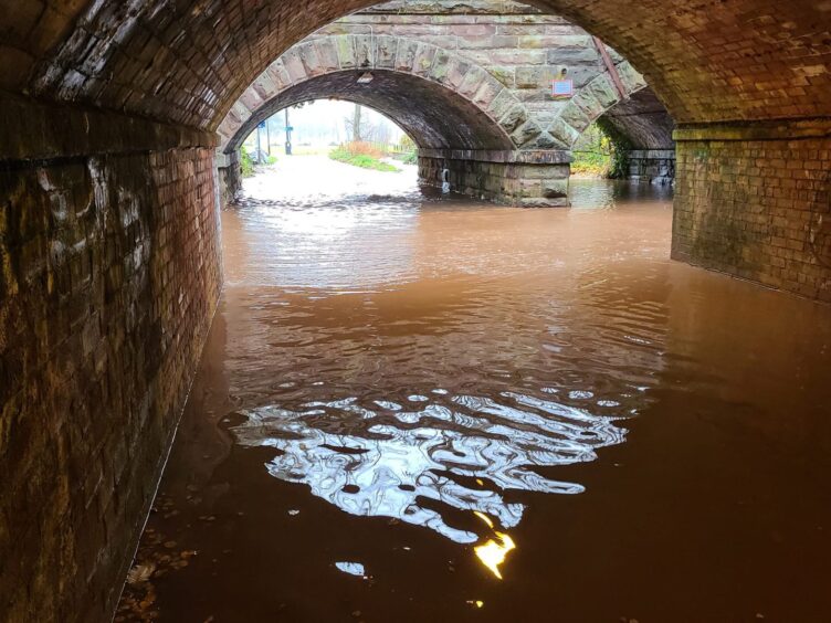 Rail tunnels with deep flood water completely covering footpaths.