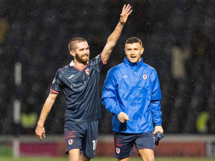 Sam Stanton raises his left arm in the air to celebrate with someone in the crowd after a Raith Rovers win.