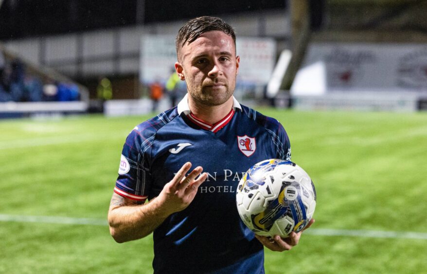 Raith Rovers striker Lewis Vaughan clutches the match ball and holds up three fingers after scoring a hat-trick.