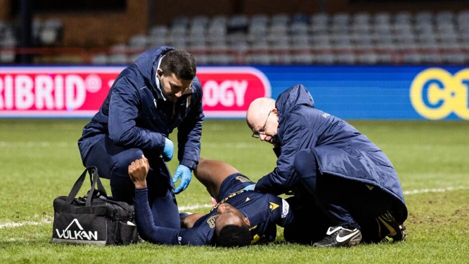 Zach Robinson receives treatment as Dundee are beaten by Celtic. Image: SNS