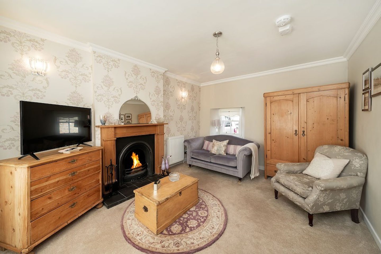 Spacious lounge in Thrums Cottage, featuring cosy furnishings and a fireplace.