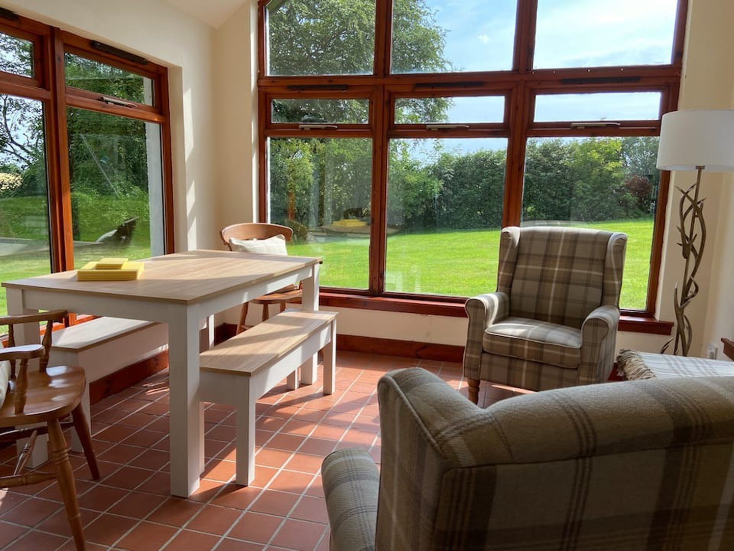 The 'sun lounge' in the Angus Airbnb featuring cosy seating and large windows with views of the garden.