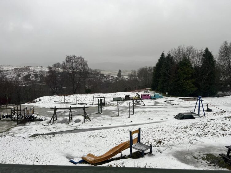 Snow covered play area at Auchingarrich wildlife centre with Comrie in distance