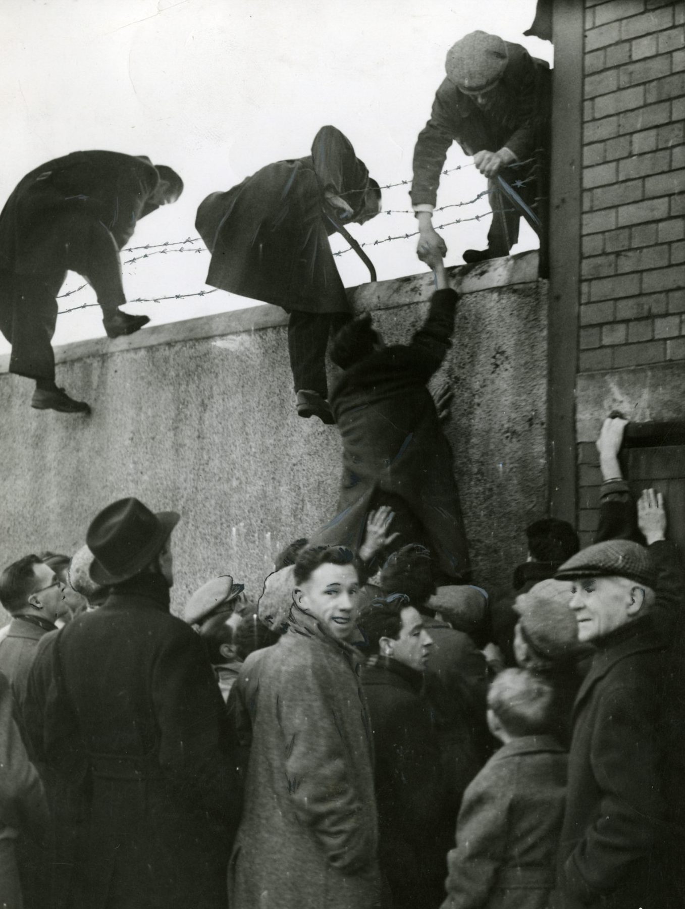 Fans scaling the walls at Dens Park so they can watch the game in 1949. Image: DC Thomson.