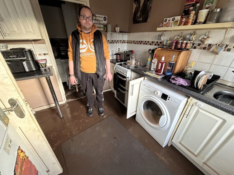Andrew McIntosh surveys the damage to his kitchen by Storm Gerrit flooding.