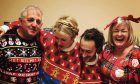 Edith and her husband Tom share a giant Christmas jumper for two, flanked by her parents for some festive fun. Image: Supplied.