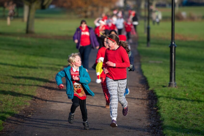 Two girls running and chatting on the Inch View primary Santa run