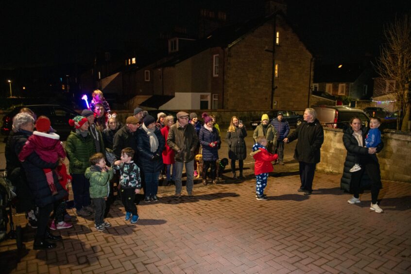 Crowd of families standing outside address in the Craigie area of Perth waiting for the window display to be illuminated
