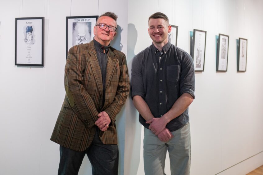 Ian Ferguson and Tom Smith stand in front of their framed poems and illustrations.
