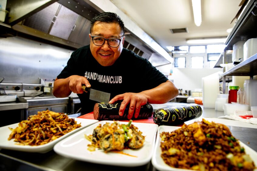 Perth takeaway boss Pete Chan smiling broadly as he prepares food in his China China takeaway in Perth.