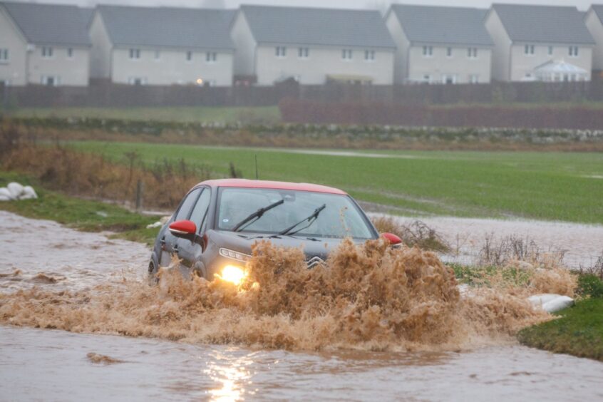Car driving through deep flood water on the A85 Crieff to Perth road at Huntontower