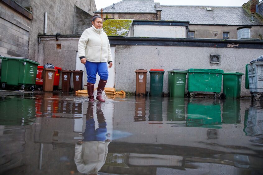 Nongmay Buncharoen in wellies walking through water at the rear of the Mae Ping restaurant in Perth.