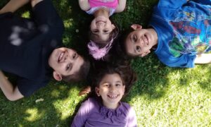 Mo and Elaine Al-Hamdan and their siblings Zuhair and Layan lying with their heads together on the grass