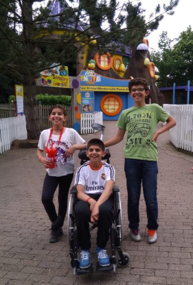 Mo Al-Hamdan in wheelchair at a fun park with his brother and sister